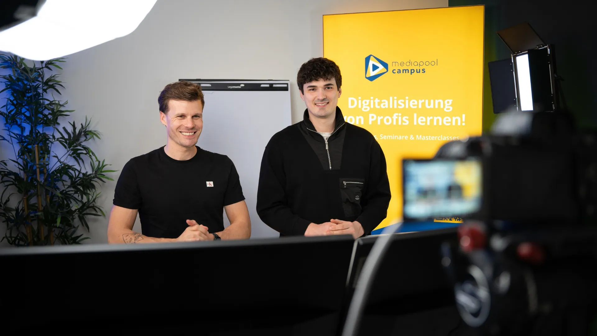 mediapool campus – Zwei Referenten im Aufnahmestudio mit Kamera und Campus-Roll-up