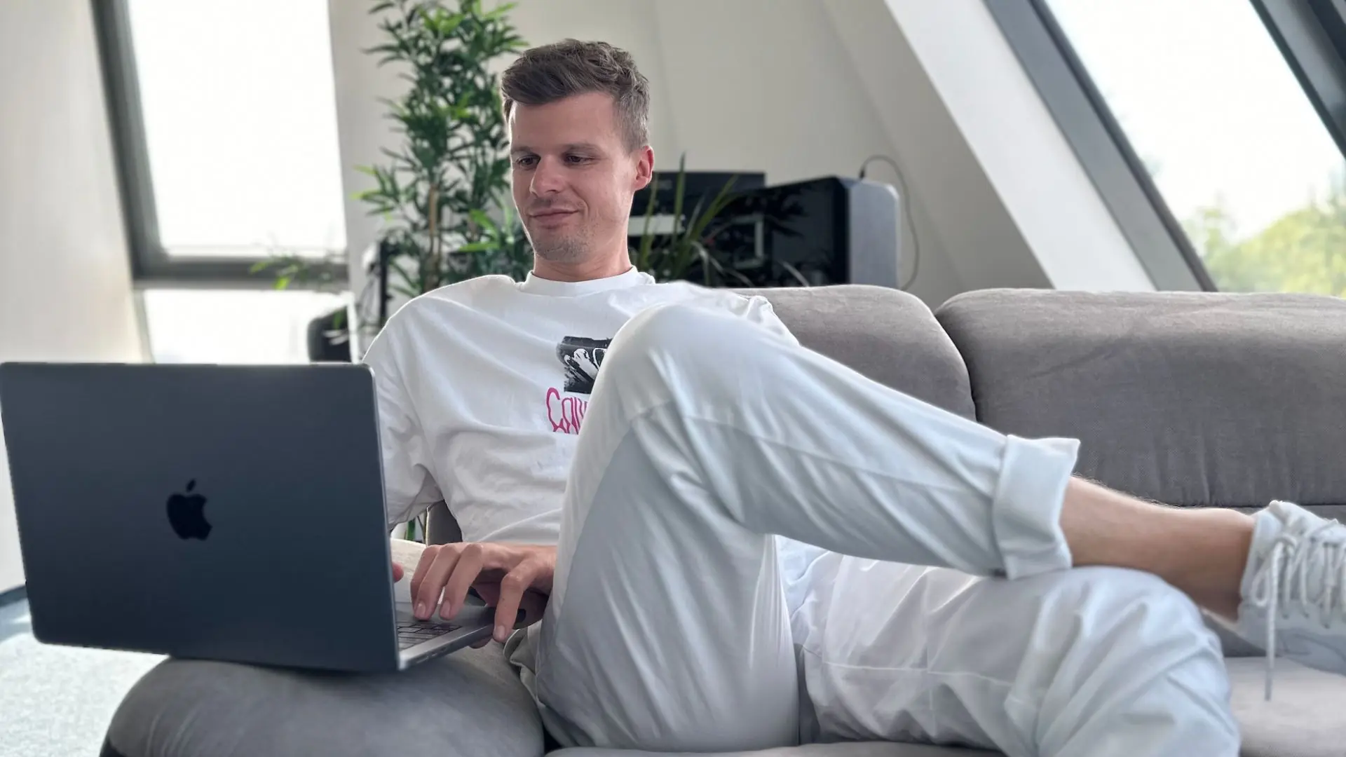 Teammitglied arbeitet entspannt mit Laptop auf dem Sofa im hellen Büro