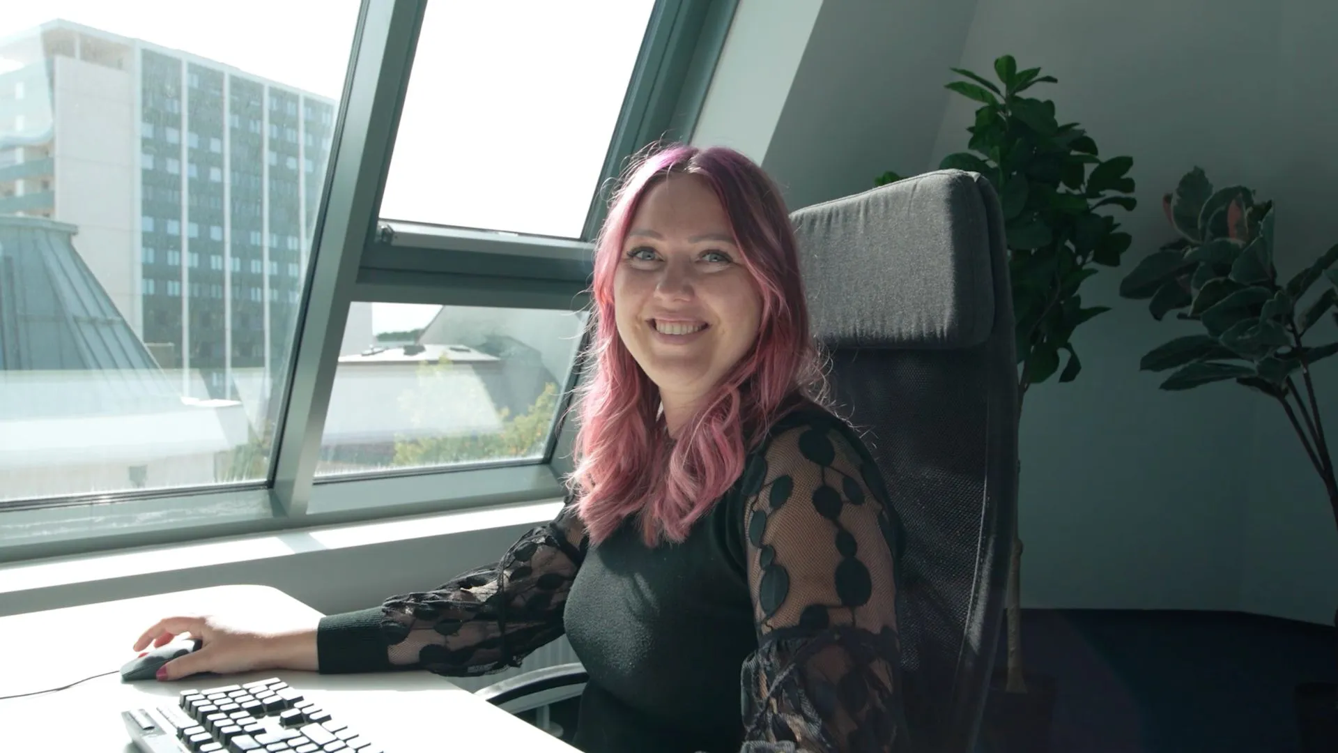 Beraterin von mediapool am Schreibtisch im hellen Büro, freundlich in die Kamera blickend