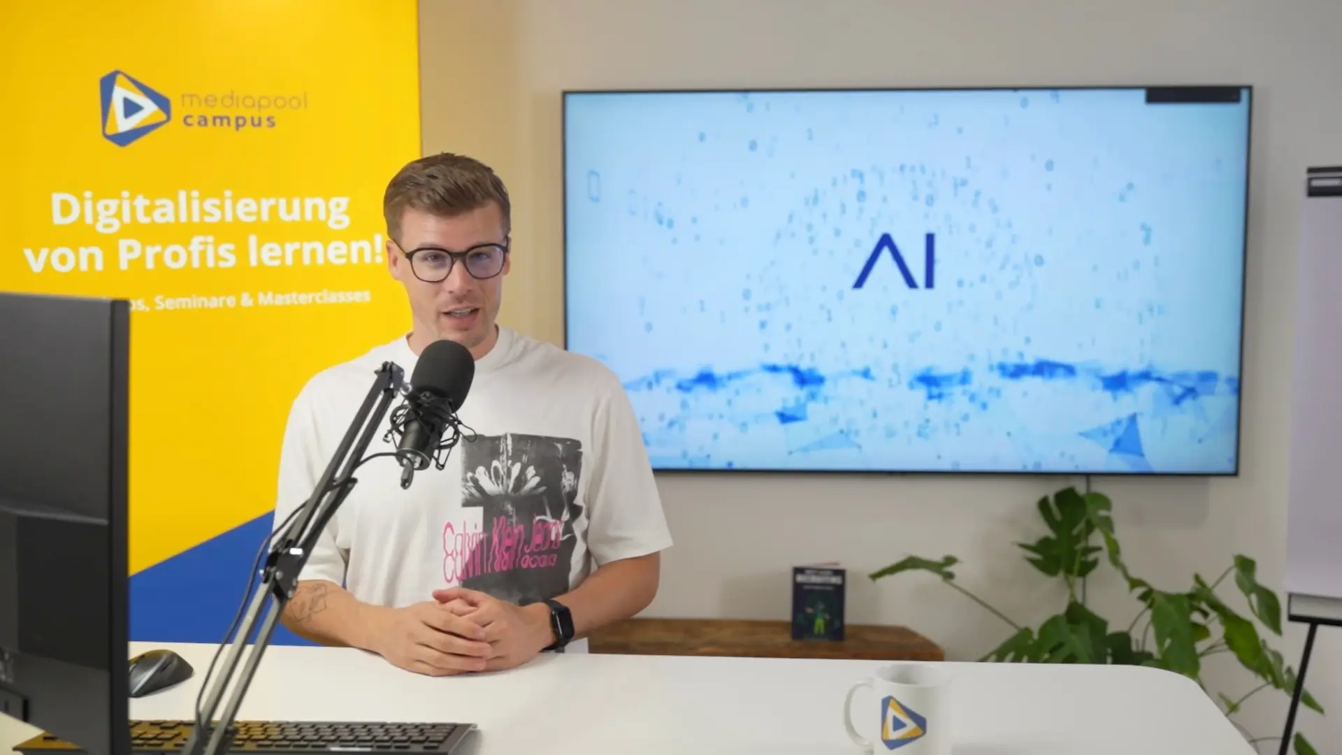 Referent im mediapool campus Studio vor Mikrofon; Hintergrund Bildschirm mit KI-Logo und Campus-Roll-up